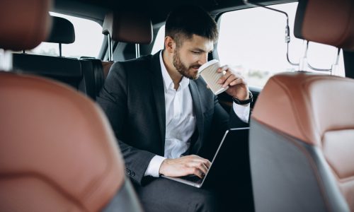 handsome-business-man-working-computer-car-scaled.jpg
